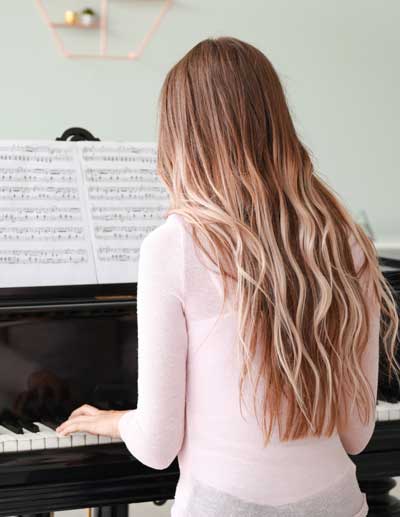 Jugendliche spielt Klavier Ansicht von hinten